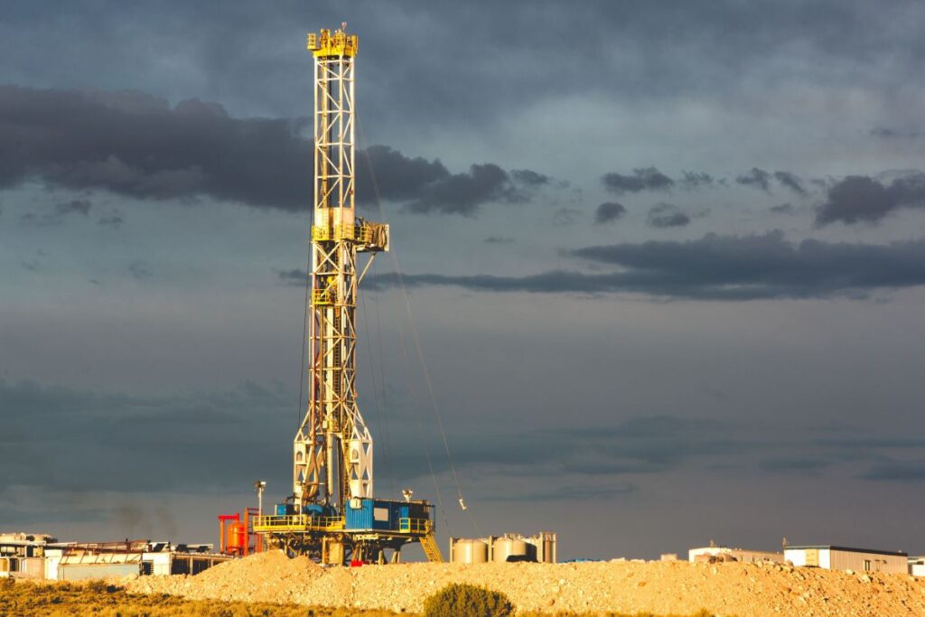A rig drills into the earth against a cloudy sky.