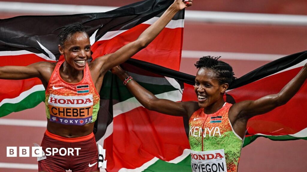 Beatrice Chebet and Faith Kipyegon smile and trail Kenyan flags behind them while celebrating on a running track after winning gold and silver respectively in the women's 5,000m at the World Athletics Championships in Tokyo